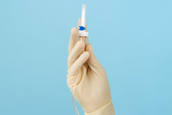 doctor holds a catheter in their hand on a blue background