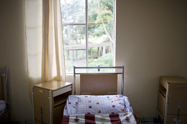 an empty hospital bed and side table in front of a window in a hospital located in Democratic Republic of the Congo