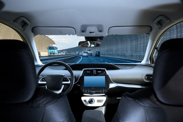 Cockpit of driverless car driving on highway viewed from rear seat